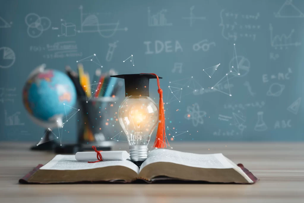 Graduation cap and glowing light bulb on open book